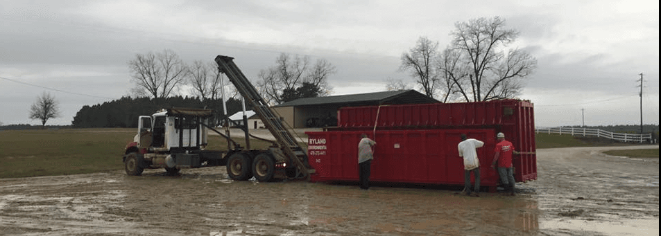 Ryland Environmental crew delivering roll-off container in muddy conditions