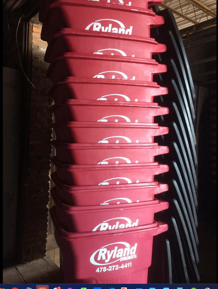 Stack of brand new red Ryland Environmental trash cans ready for delivery